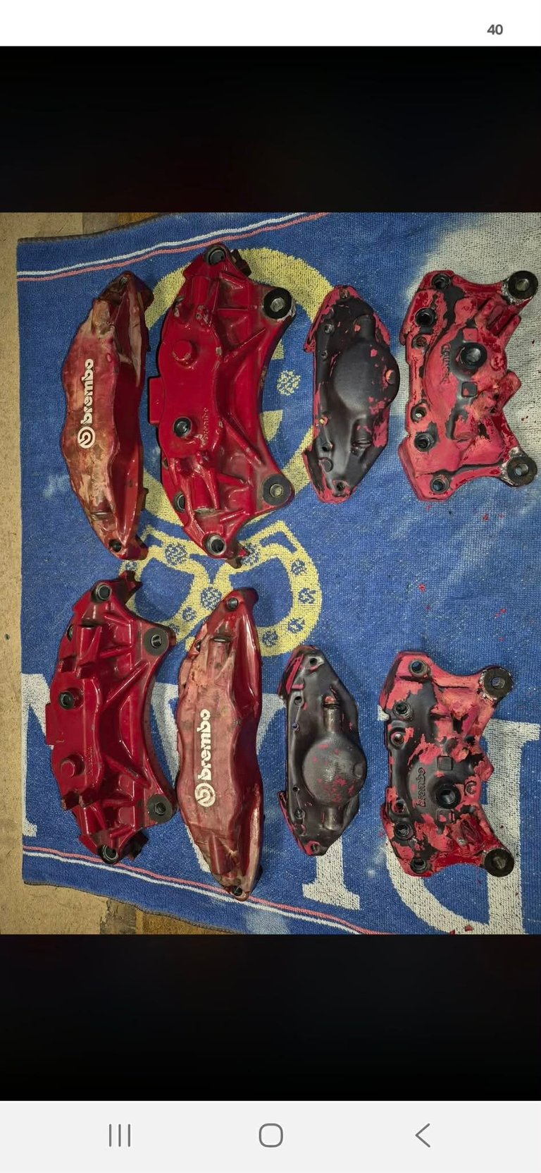 Collection of red Brembo brake calipers displayed on blue Brembo branded mat